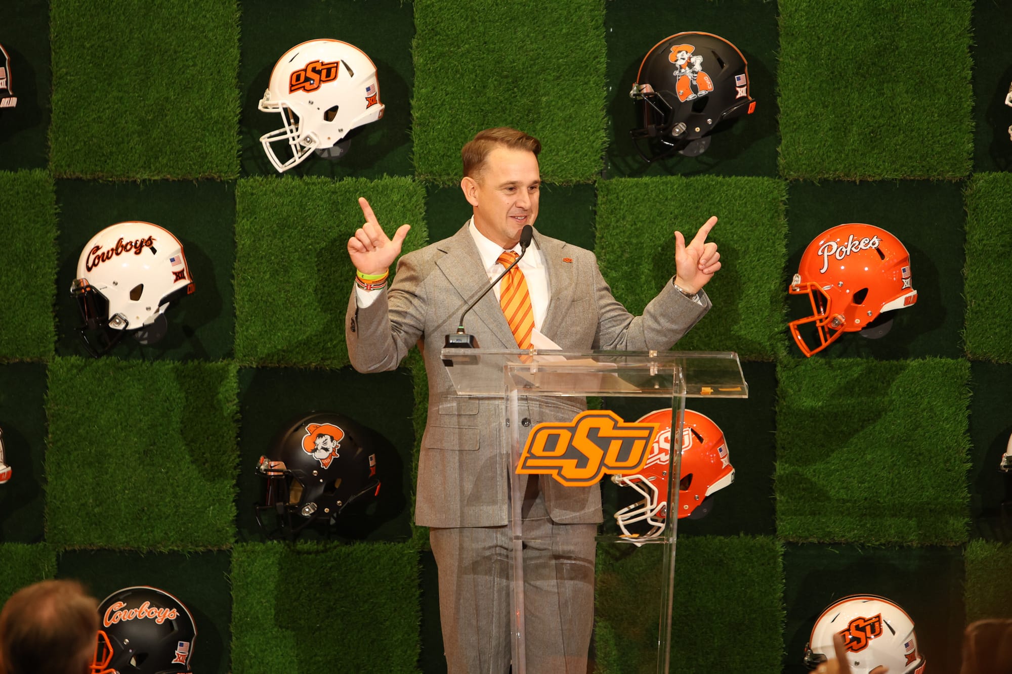 Eric Morris makes OSU Pistols Firing hand sign during introductory press conference as Oklahoma State head football coach