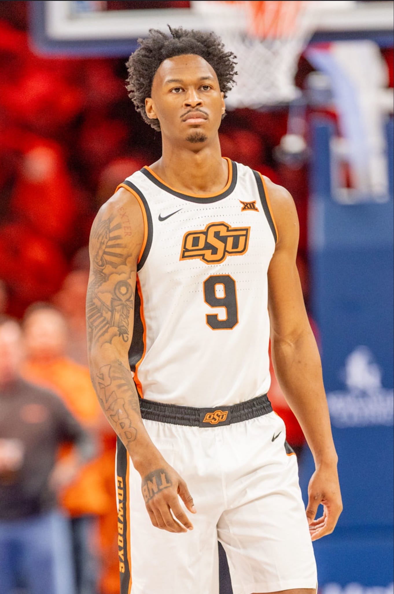 Oklahoma State guard Anthony Roy wearing number 9 white Cowboys jersey stands on the court during a game, looking ahead with a focused expression