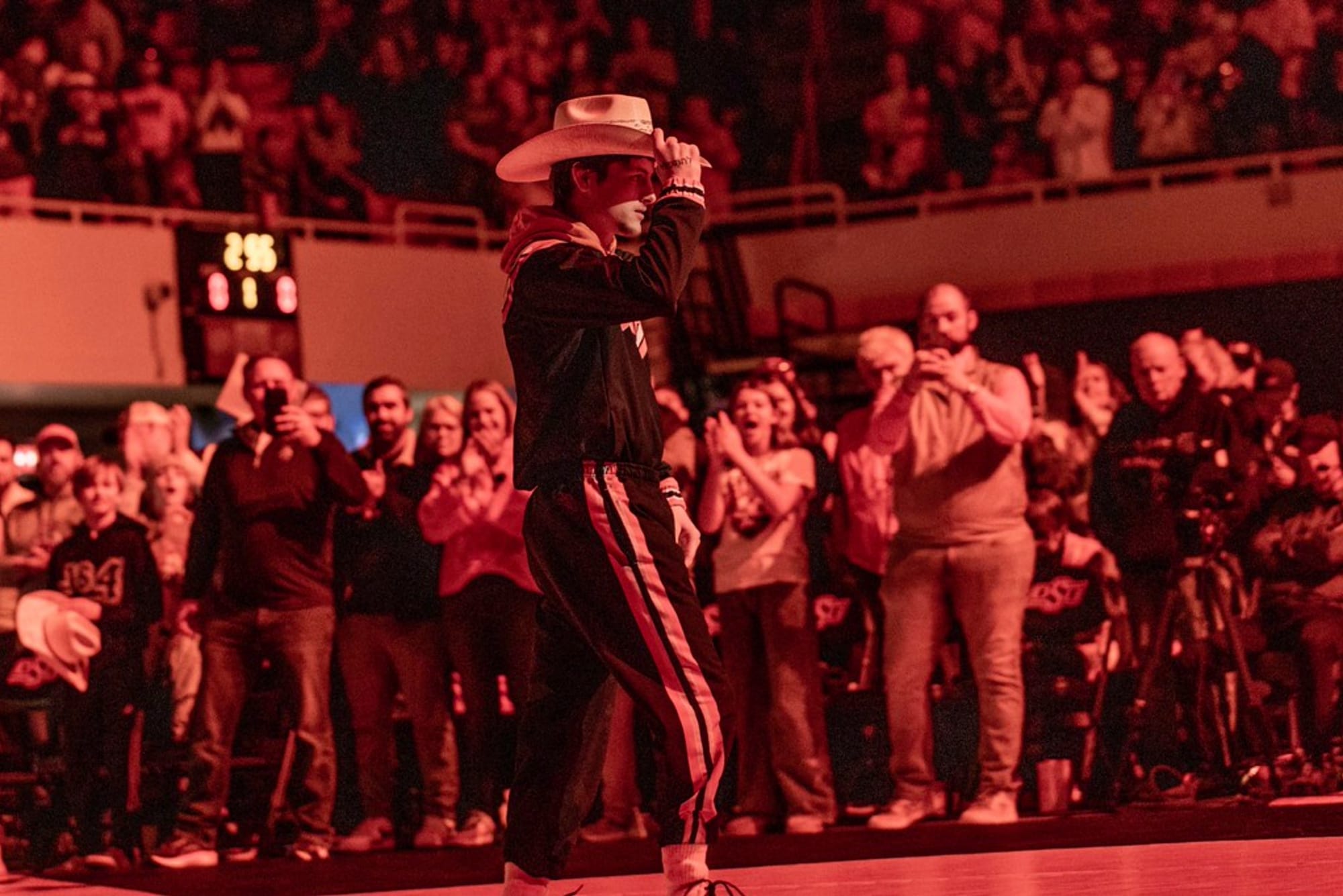 Oklahoma State freshman Jax Forrest tips his cowboy hat as he walks onto the mat under red lighting before his collegiate debut at the Cowboys' Bedlam dual Jan. 11, 2026, in Stillwater.