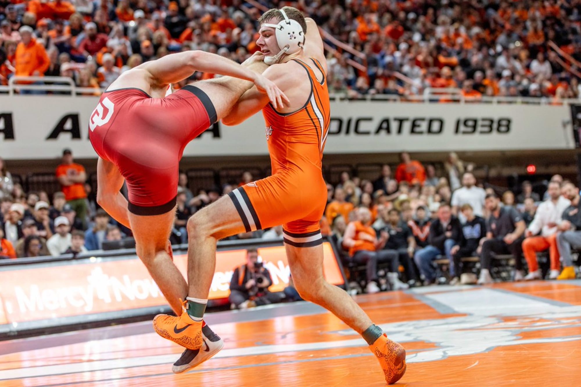 Oklahoma State wrestler Kody Routledge in orange singlet executes takedown on Oklahoma opponent in red singlet on Jan. 11, 2026, at Gallagher-Iba Arena in Stillwater, Oklahoma.