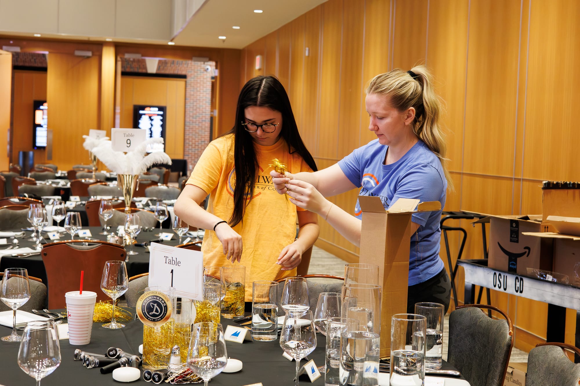 Elaine McKenzie and Landry Bledsoe arrange table decorations in the OSU Alumni Center ballroom ahead of the Stillwater Chamber of Commerce Awards Gala.