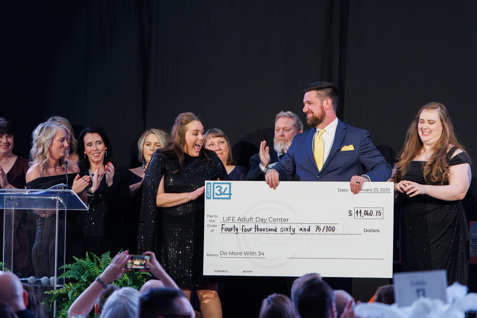 Leadership Stillwater Class 34 members present a ceremonial check for $44,060.75 to LIFE Center Adult Day Services on stage at the Stillwater Chamber Awards Gala.