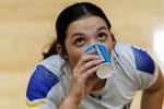 A closeup photo of a volleyball player drinking out of a powerade branded cup with eyes looking up