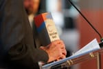 Steve Irby holds a wooden Hall of Fame Award trophy with red, blue, and gray paint strokes at a clear podium during the Stillwater Chamber Awards Gala.