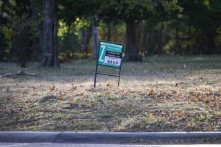 Public hearing sign on vacant lot at 802 S. Western Road showing rezoning request from RSS to O with hearing dates of Nov. 4, 2025 and Nov. 17, 2025
