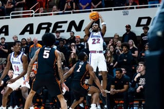 Kansas guard Darryn Peterson (22) rises for a jump shot over OSU defenders Vyctorious Miller (5) and Kanye Clary (7) during Kansas' 81-69 win at Gallagher-Iba Arena.