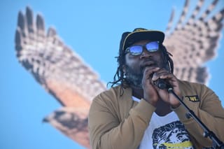 Petty Fox singer Damion Fox performs at a microphone on the KICKER Soundstage at Block 34, a large image of a hawk in flight projected on the screen behind him.