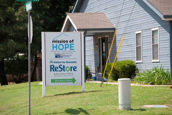 Mission of Hope sign stands in front of light blue building in Stillwater. The organization also houses Habitat for Humanity ReStore at the South Perkins Road location.