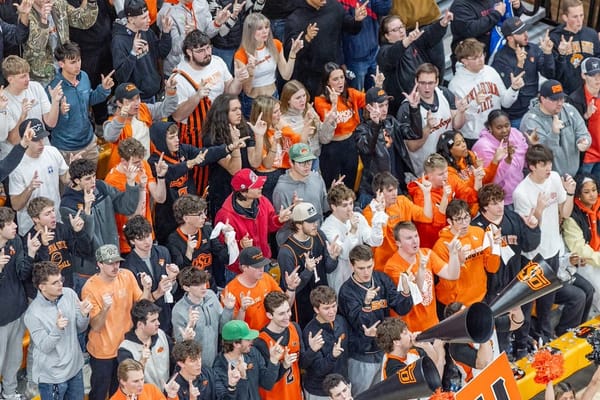 Crowd of OSU students in orange and black apparel making finger pistol gestures during basketball game against BYU at Gallagher-Iba Arena